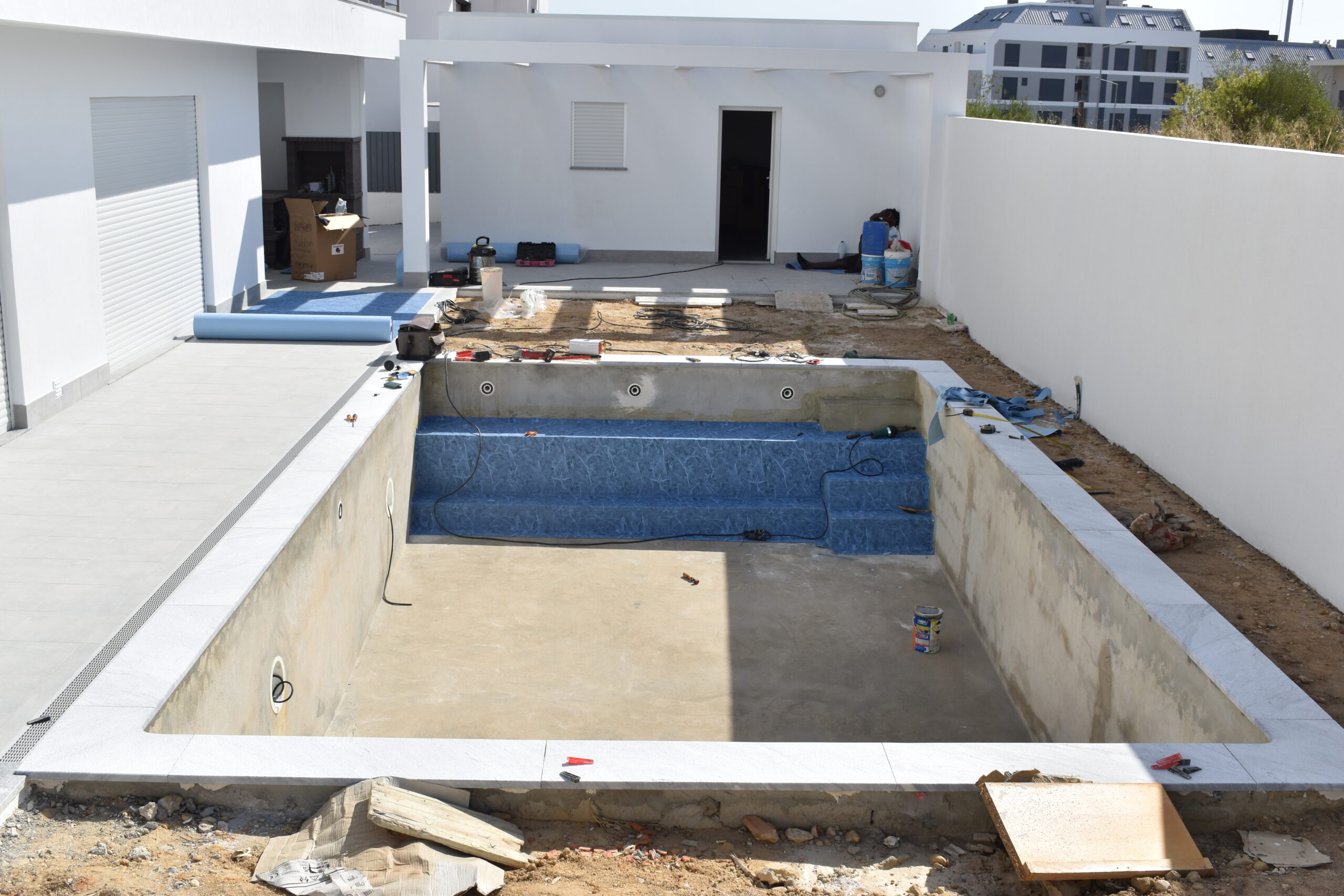 Residential swimming pool in final construction phase, with interior finish applied and surrounding area being completed
